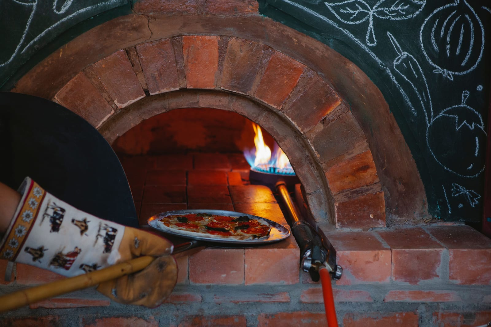 Pizza sendo assada em um forno a lenha de tijolos