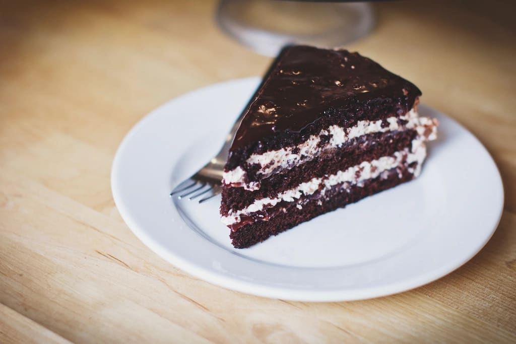 Fatia de bolo de chocolate com recheio cremoso num prato branco