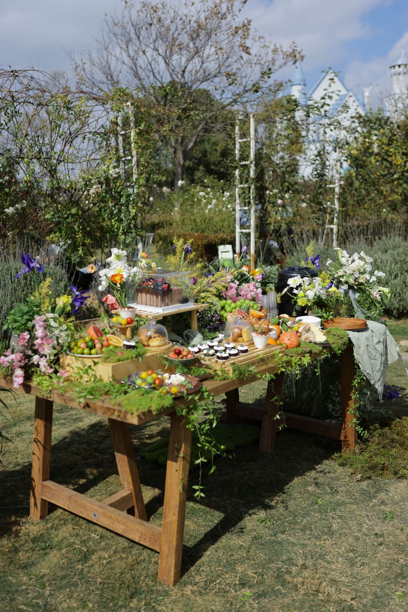 Mesa de doces, frutas e flores servida no jardim