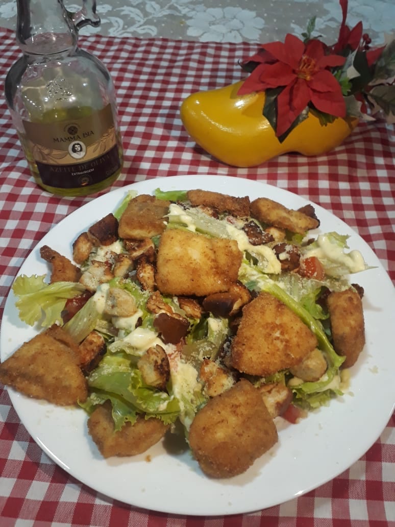 Prato de salada verde com empanados e croutons, ao lado de um tamanco holandês amarelo com flores